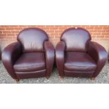 A pair of contemporary tub chairs upholstered in a deep brown / aubergine leather.