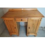 A Victorian pine desk with centre drawer flanked either side by cupboards,