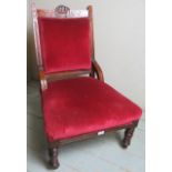 A Victorian show wood framed low library chair upholstered in a deep red material and terminating