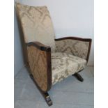 A 20th Century oak framed nursing chair upholstered in a floral green material.