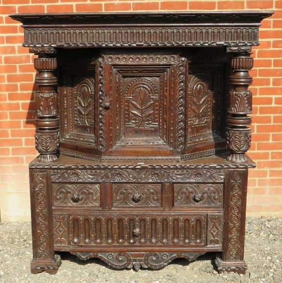 A large part 16th Century carved oak court cupboard with a central cupboard door flanked either