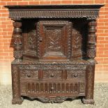 A large part 16th Century carved oak court cupboard with a central cupboard door flanked either
