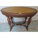 A Victorian carved oak oval side table with an inset tooled leather top over curved cross