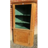 A 19th century stripped pine corner cupboard with an open green painted area to top with three