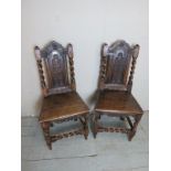 A pair of 17th Century oak hall chairs with carved motifs and spiral twist uprights and lower front