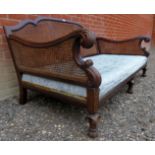 A large 19th Century carved oak framed bergere settee with decorative scroll arms over a floral