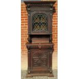 A tall 19th Century carved oak Flemish cabinet with an arched leaded stained glass cupboard to top