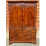 A Georgian mahogany linen press with double doors opening to reveal internal linen slides over two