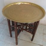 A brass topped Benares table with a turned folding base.