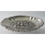 An oval silver dish with heavily embosse