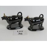 A pair of antique black glazed cow cream