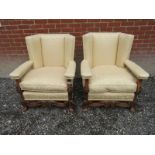 A pair of early 20th Century oak framed large high back open sided armchairs with carved legs and