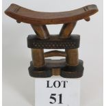 A carved hardwood tribal African headrest with two column support and zigzag decoration.