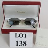 A pair of Cartier chrome unisex sunglasses with original guarantee and red leather box.