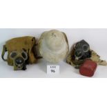 Two WW2 gas masks with bags, one marked 1941 and a war issue white pith helmet.