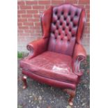 A reproduction Georgian style leather wing armchair. 106cm high x 82cm wide x 82cm deep (approx).