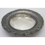 A silver dish heavily embossed around th