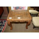 A SMALL CARVED WOODEN TABLE WITH GLASS INSET TOP