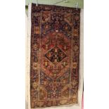 A WOVEN WOOLEN FLOOR RUG with central diamond lozenge, stylised floral field and guard border