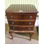 A REPRODUCTION MAHOGANY FINISHED SMALL THREE DRAWER CHEST supported on cabriole legs