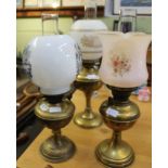 THREE BRASS BASED OIL LAMPS with decorated glass shades