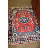 A WOVEN WOOLEN GEOMETRIC PATTERNED RED & BLUE FLOOR RUG