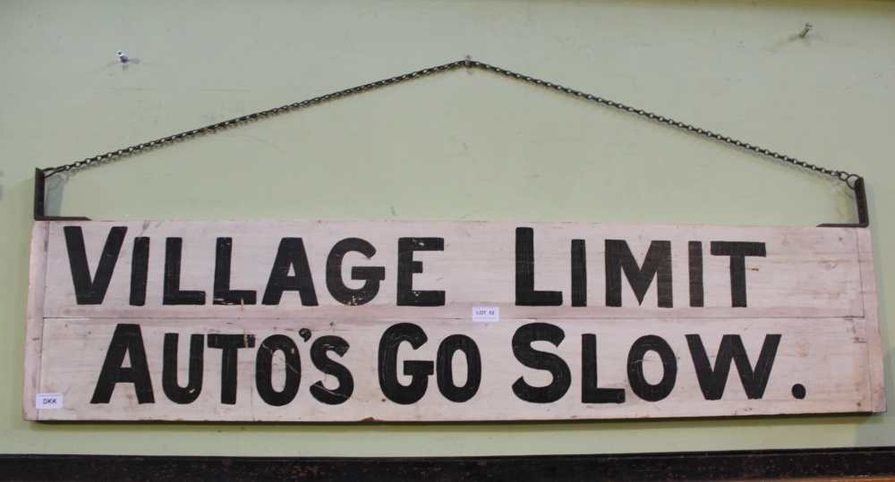 A NOVELTY PAINTED WOODEN HANGING SIGN bearing the legend "Village Limit, Auto's go Slow"