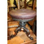 A 19TH CENTURY CARVED WOODEN BASED PIANO STOOL with rexine studded pad top