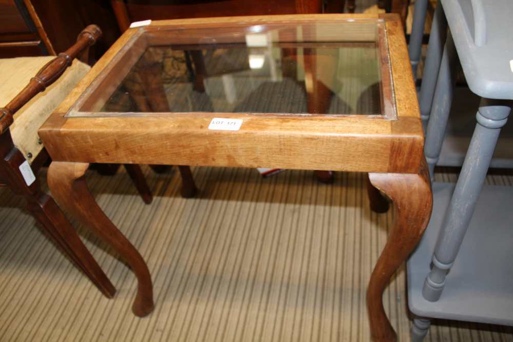 AN INSET GLASS TOPPED COFFEE TABLE fashioned from a cabriole legged stool