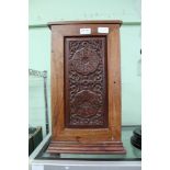 AN IMPORTED HARDWOOD CABINET with carved panel single door