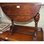 AN OAK REVOLVING TOP TWO FLAP COFFEE TABLE on turned baluster and block supports on an "H" shaped