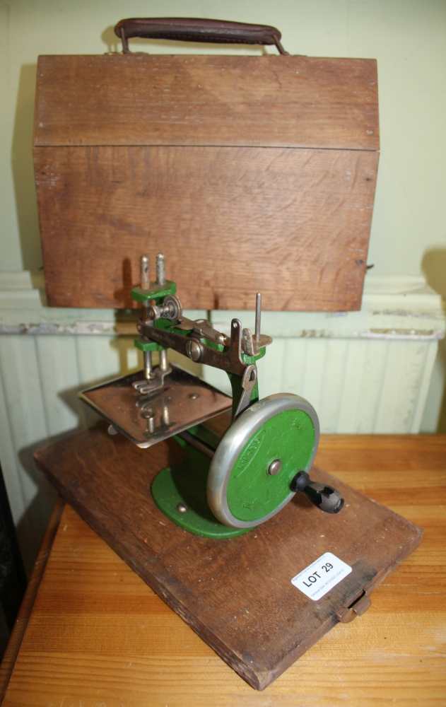 A MINIATURE COLLECTABLE METAL MANUAL SEWING MACHINE bearing the name "Grain", mounted on a wooden