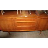 A LONG AND LOW TEAK FINISHED RETRO SIDEBOARD with three central drawers, flanked by two cupboard