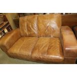 A WELL WORN COFFEE COLOURED LEATHER TWO PERSON SETTEE