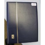 A NAVY BLUE FINISHED STAMP ALBUM, containing numerous unmounted stamps of the world