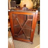 AN EARLY 20TH CENTURY MAHOGANY FINISHED HANGING CORNER CUPBOARD with bar glazed door