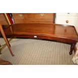 A 19TH CENTURY MAHOGANY FINISHED CURVE TOP WINDOW SEAT supported on four turned short legs, with