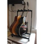 A WARWICK BRANDED METAL & FOAM GUITAR STAND containing an Encore acoustic guitar, and a Scottish
