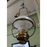 A HANGING BRASS FINISHED METAL FRAMED PARAFFIN LAMP with opaque glass chimney and milk glass shade