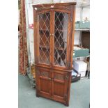 AN OLD CHARM BRANDED OAK FINISHED FREE STANDING CORNER CUPBOARD with leaded upper doors
