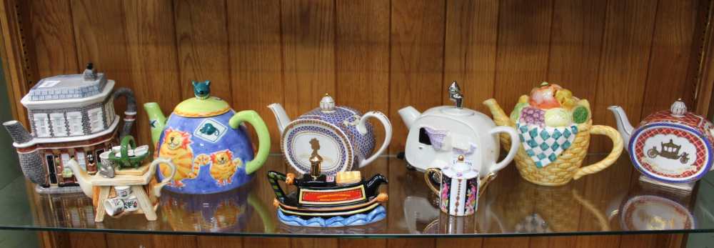 A SHELF FULL OF NOVELTY TEAPOTS VARIOUS