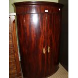 A 19TH CENTURY MAHOGANY HANGING BOW FRONT CORNER CUPBOARD, having two plain doors opening to