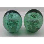 TWO VICTORIAN GREEN GLASS DUMP WEIGHTS with floral inclusions, 11cm and 11.5cm high