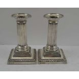 HAWKSWORTH, EYRE & CO. LTD A PAIR OF SILVER COLUMN CANDLESTICKS, Sheffield 1915, on square stepped
