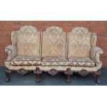 AN EARLY 20TH CENTURY WINGBACK THREE SEATER SOFA, on carved show wood lower frame with scallop shell