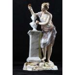 A CONTINENTAL PORCELAIN FIGURINE depicting a classical sculptress at work, classically draped,