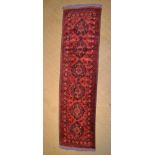 A PERSIAN RUNNER, pigeon red ground, six central motifs, deep floral stylised guard border
