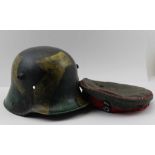 A GERMAN FIRST WORLD WAR STEEL HELMET, (possibly later camouflage painted) together with a WWI