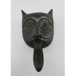 A 19TH CENTURY BRONZE DOOR KNOCKER in the form of a cat's face with glass eyes, the outstretched