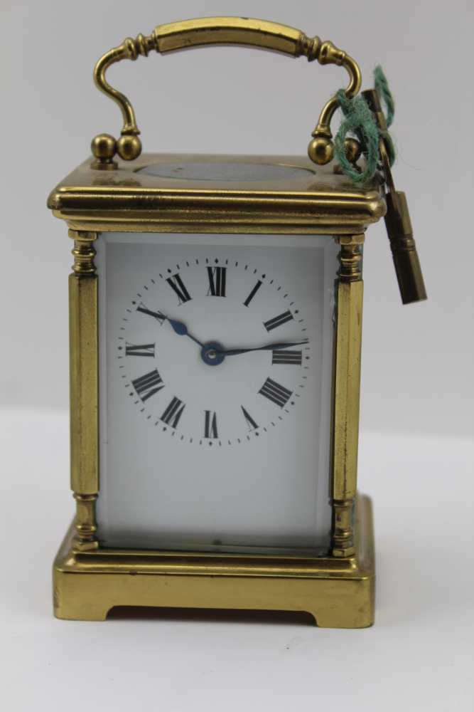 A BRASS FRAMED CARRIAGE CLOCK, with bevelled glass panels, white enamel dial with Roman numerals,